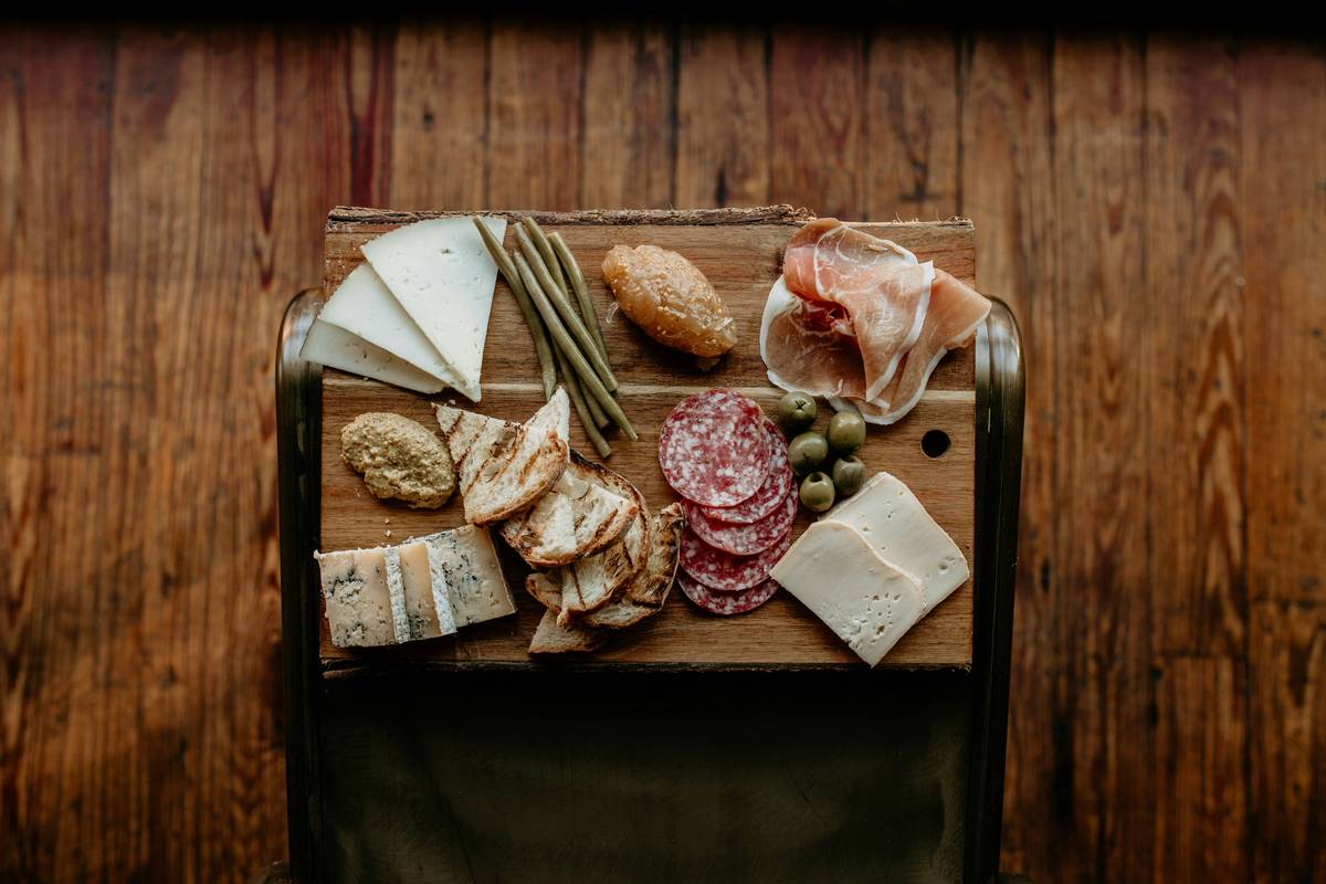 Wooden cheese serving board with assorted cheeses and a microplane grater